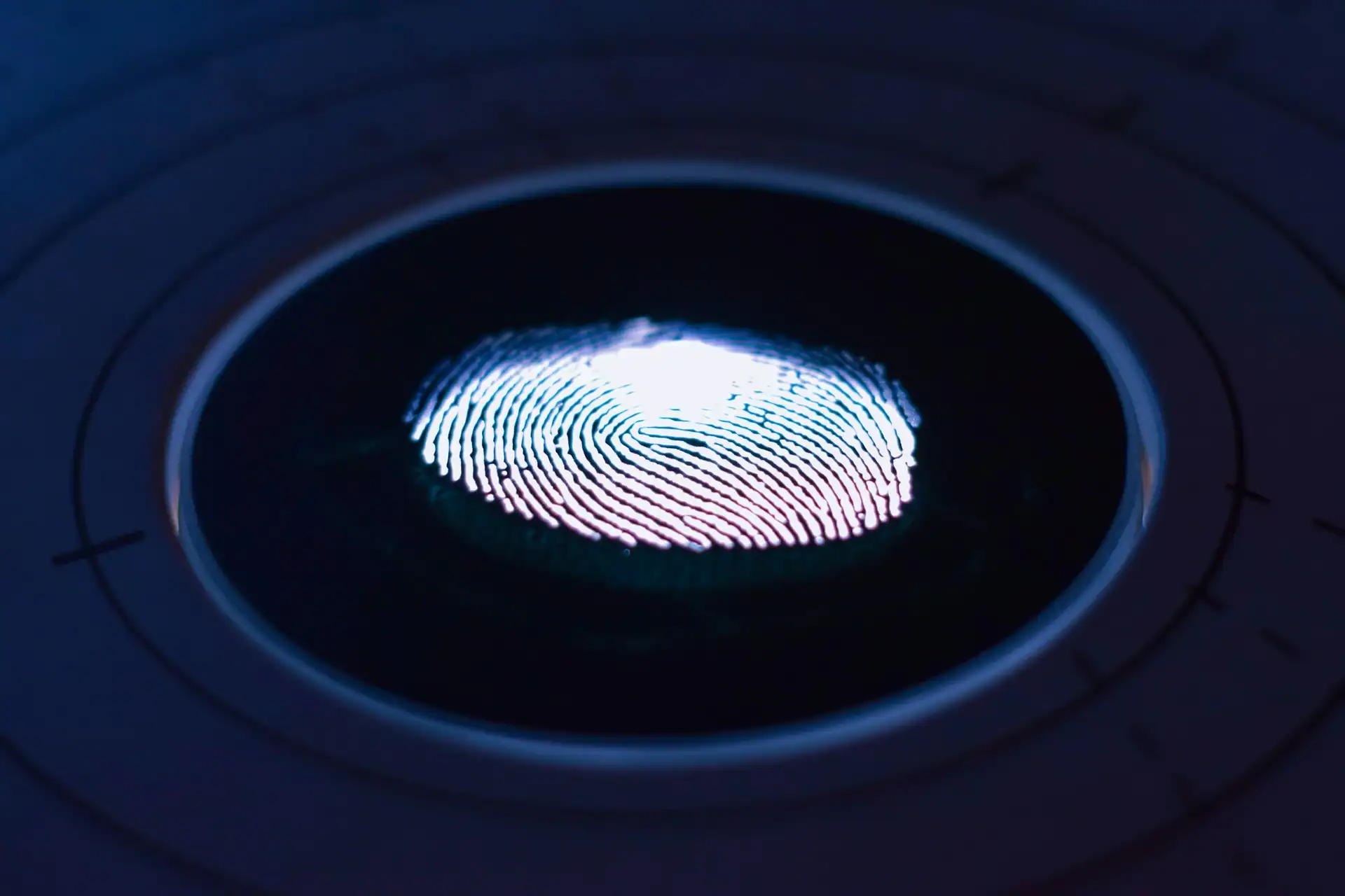 Nahaufnahme eines leuchtenden Fingerabdrucks auf einem runden, biometrischen Scanner in einer dunklen, futuristischen Umgebung mit blauer Beleuchtung