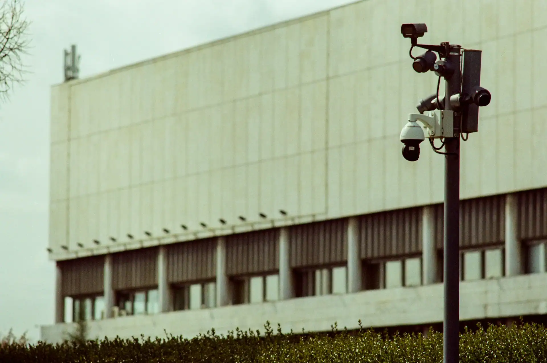 Überwachungskameras an einem Mast vor der Fassade eines großen modernen Gebäudes